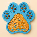 Coathaus paw-shaped lick mat in ocean blue with peanut butter in the centre grid and kibble in the toe pads